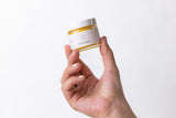 Natural organic nipple balm in a smal jar - held in a hand